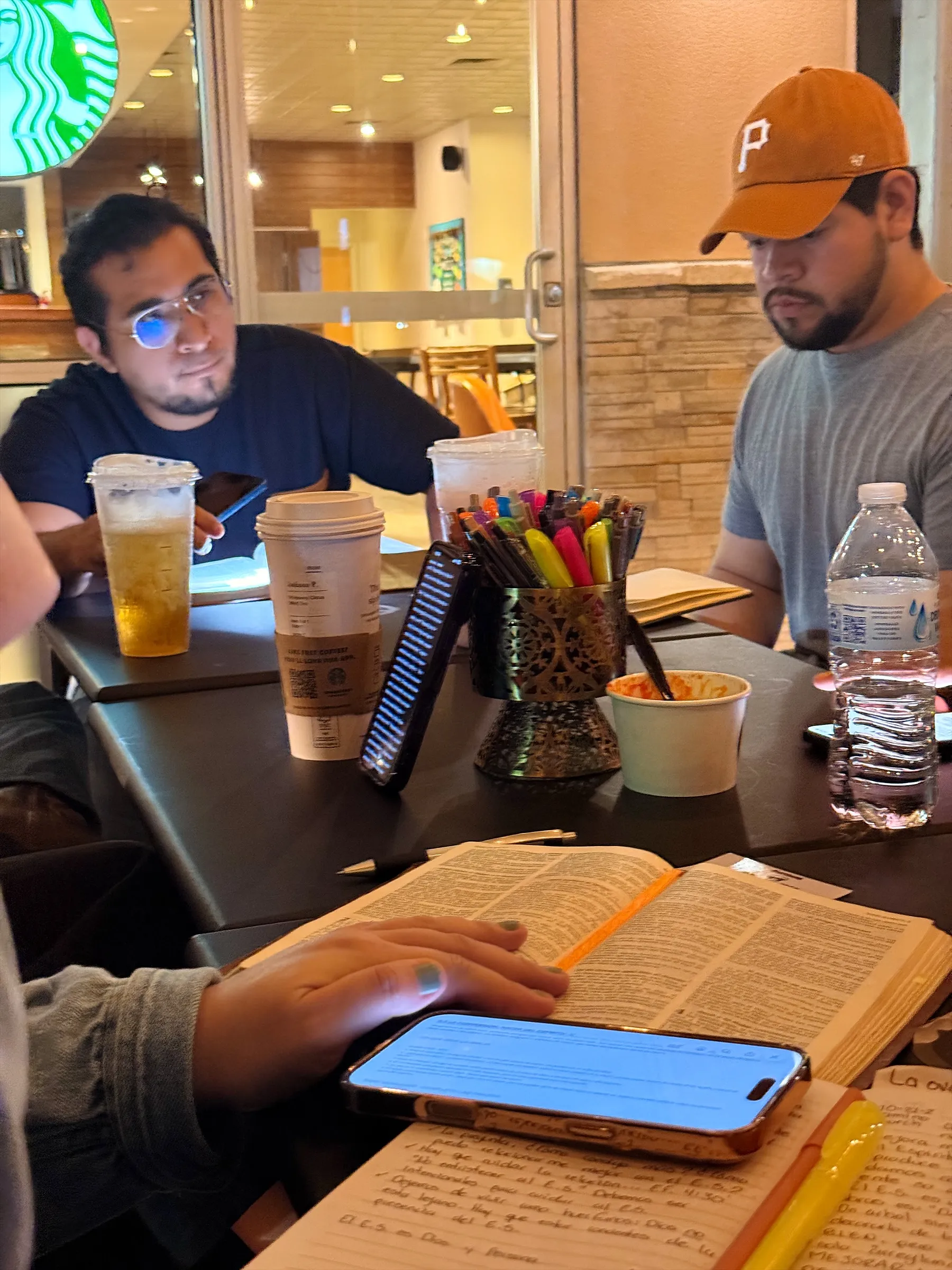 Biblia abierta, café y colores sobre la mesa de un estudio bíblico